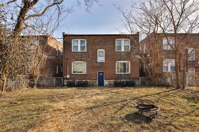 back of house with brick siding, a fire pit, and central AC