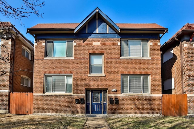 view of front of home featuring brick siding and fence