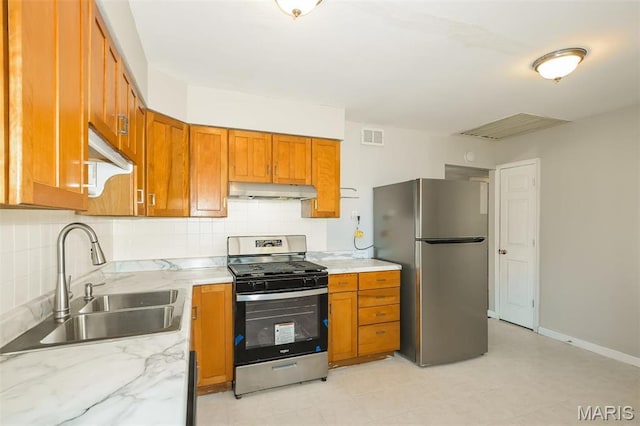 1235 Flicker Dr, Florissant, MO 63031 - kitchen with stainless steel appliances, under cabinet range hood, brown cabinetry, backsplash, and light stone countertops