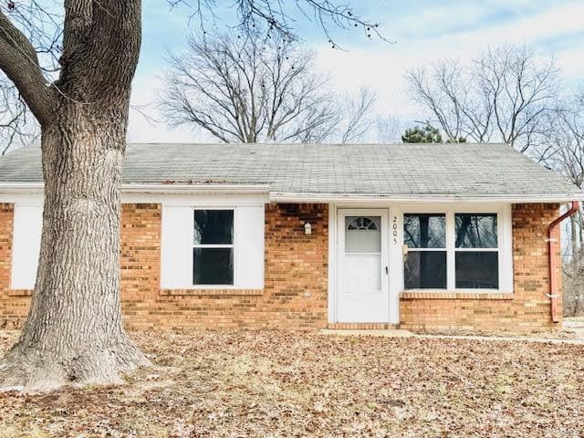 view of front of home with brick siding and roof with shingles