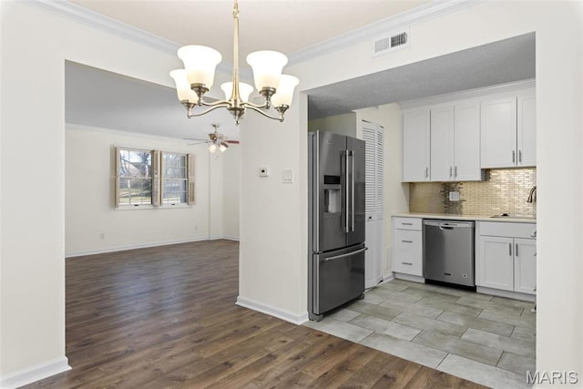 1773 High School Dr, Brentwood, MO 63144 - kitchen with stainless steel appliances, a chandelier, white cabinetry, ceiling fan, and backsplash