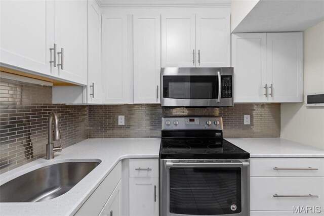 1773 High School Dr, Brentwood, MO 63144 - kitchen featuring stainless steel appliances, a sink, white cabinetry, and backsplash