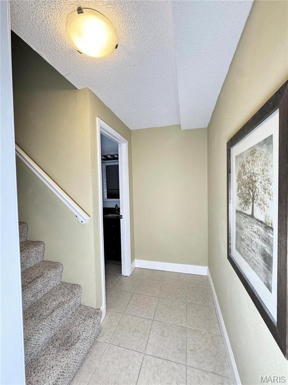 5284 Summer Cir, Imperial, MO 63052 - stairs with a textured ceiling, tile patterned floors, and baseboards