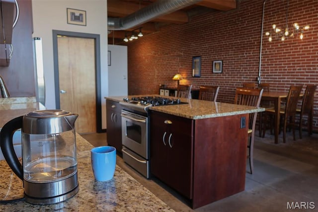 1015 Washington Ave Unit 609, Saint Louis, MO 63101 - kitchen featuring stainless steel gas stove, dark brown cabinetry, light stone countertops, a kitchen island, and brick wall