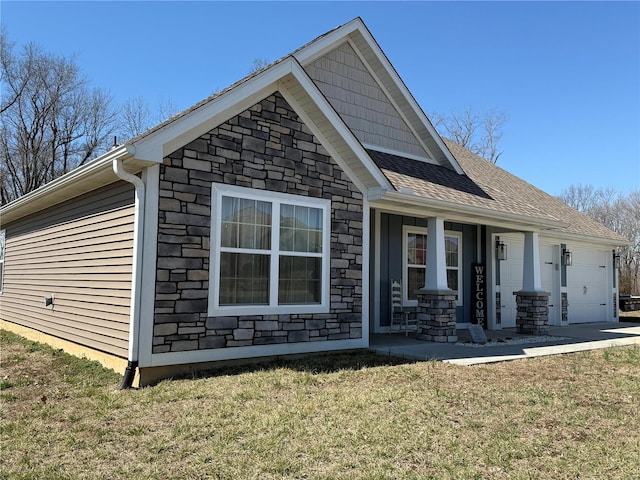 view of property exterior with stone siding, an attached garage, covered porch, and a lawn