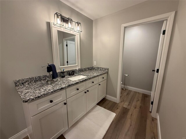bathroom with wood finished floors, vanity, and baseboards