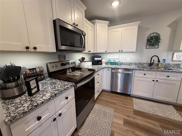 379 Lakeview Cpe, Girardeau, MO 63701 - kitchen featuring appliances with stainless steel finishes, a sink, wood finished floors, white cabinetry, and stone counters