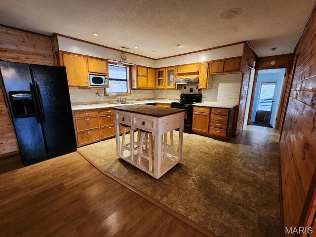 1504 Main St, Van Buren, MO 63965 - kitchen featuring black appliances, brown cabinets, under cabinet range hood, backsplash, and crown molding