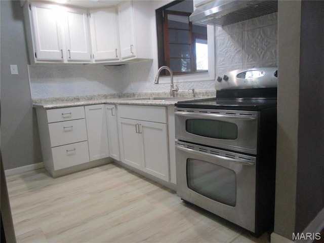 7 Pineview Ln, Collinsville, IL 62234 - kitchen featuring double oven range, wall chimney exhaust hood, a sink, decorative backsplash, and light wood-style floors