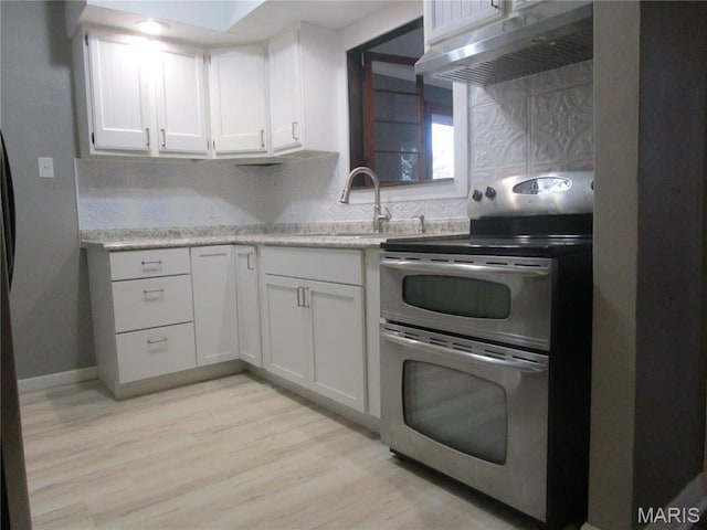 7 Pineview Ln, Collinsville, IL 62234 - kitchen featuring range with two ovens, under cabinet range hood, a sink, tasteful backsplash, and light wood finished floors