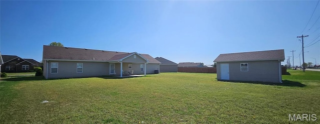 rear view of house featuring a lawn and an outbuilding