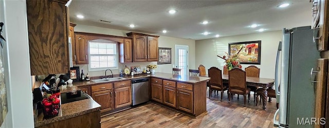 kitchen with appliances with stainless steel finishes, a sink, a peninsula, dark wood finished floors, and recessed lighting