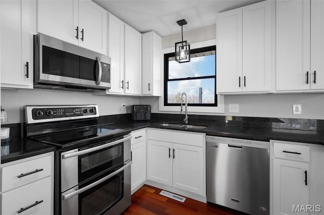 719 Green Ridge Dr, Catawissa, MO 63015 - kitchen featuring appliances with stainless steel finishes, a sink, white cabinetry, dark wood-type flooring, and decorative light fixtures
