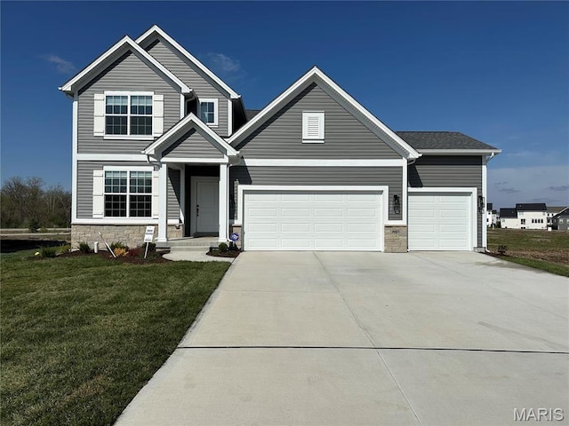traditional-style house featuring driveway, a front yard, an attached garage, and stone siding