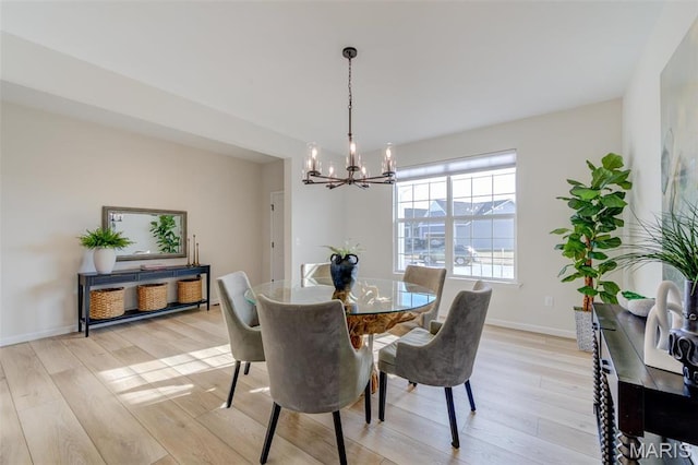 dining area with a chandelier, light wood-style flooring, and baseboards