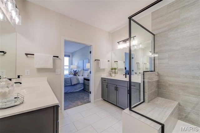 ensuite bathroom featuring a tile shower, vanity, and tile patterned flooring