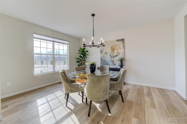 dining space featuring a chandelier, light wood finished floors, and baseboards