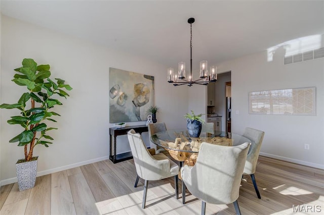 dining space with a chandelier, light wood-type flooring, and baseboards