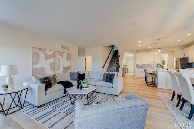 living area featuring light wood-style flooring, recessed lighting, and stairs
