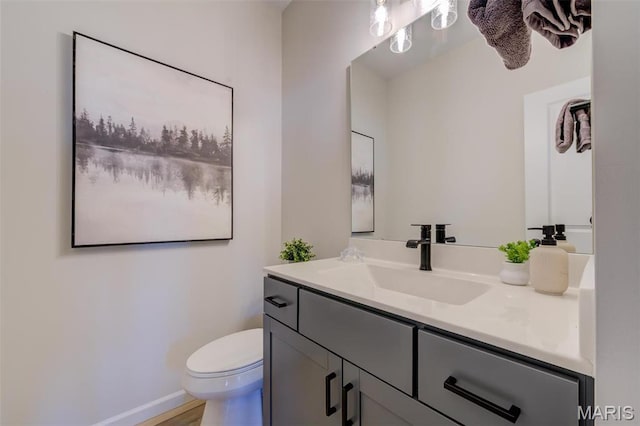 half bath featuring vanity, toilet, and baseboards