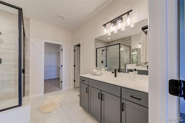 full bathroom with a shower stall, a walk in closet, vanity, and tile patterned floors