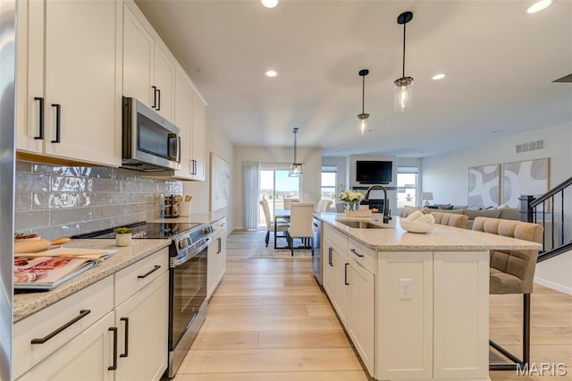 kitchen featuring appliances with stainless steel finishes, a sink, plenty of natural light, recessed lighting, and white cabinetry