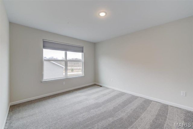 spare room featuring carpet flooring and baseboards