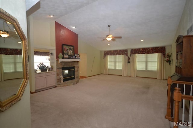 unfurnished living room featuring ceiling fan, a fireplace, light carpet, lofted ceiling, and recessed lighting