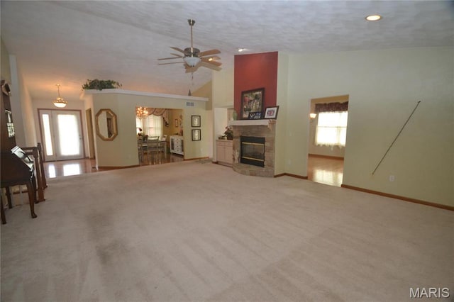 unfurnished living room featuring a ceiling fan, baseboards, a stone fireplace, carpet flooring, and lofted ceiling