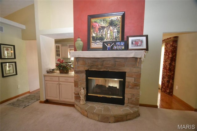 living area featuring light colored carpet, a fireplace, and baseboards