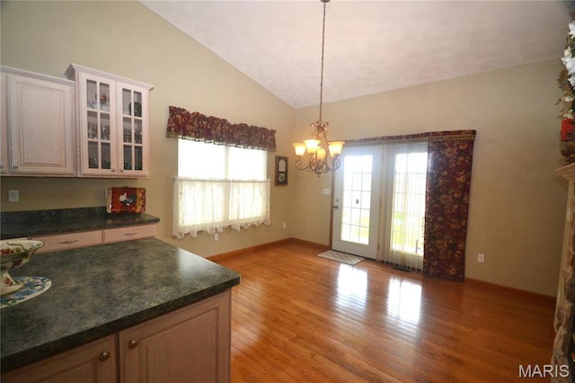 dining space featuring lofted ceiling, a chandelier, light wood-style flooring, and baseboards