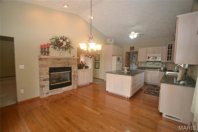 kitchen with white appliances, dark countertops, lofted ceiling, a sink, and a ceiling fan