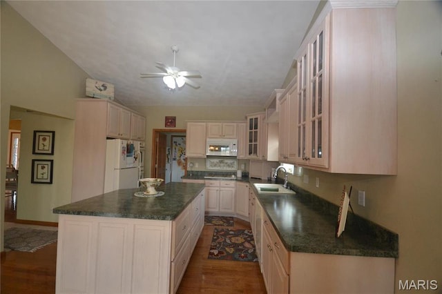 kitchen with white appliances, a sink, dark countertops, dark wood-style flooring, and a ceiling fan