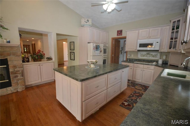 kitchen with white appliances, a sink, dark countertops, ceiling fan, and high vaulted ceiling