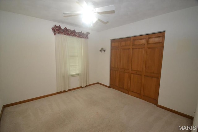 unfurnished bedroom with light carpet, baseboards, a closet, and a ceiling fan