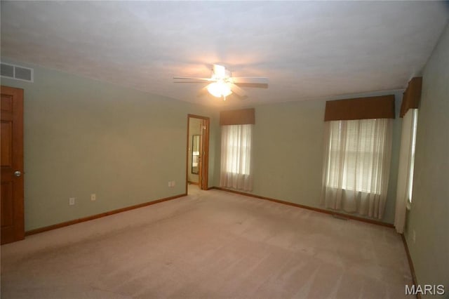 unfurnished room with a ceiling fan, light carpet, and baseboards
