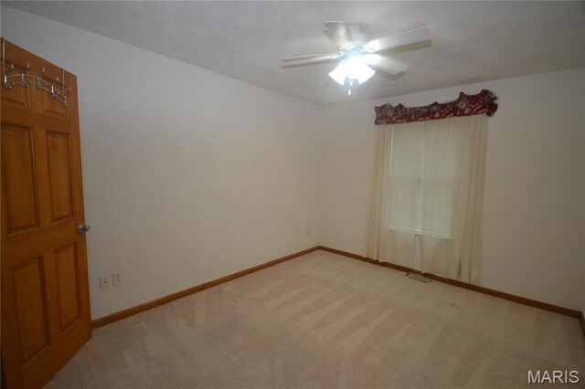 spare room with light colored carpet, ceiling fan, and baseboards