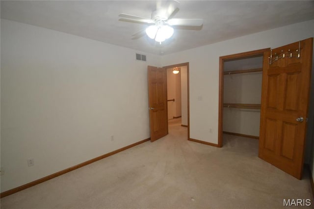 unfurnished bedroom featuring light colored carpet, baseboards, a closet, a spacious closet, and ceiling fan