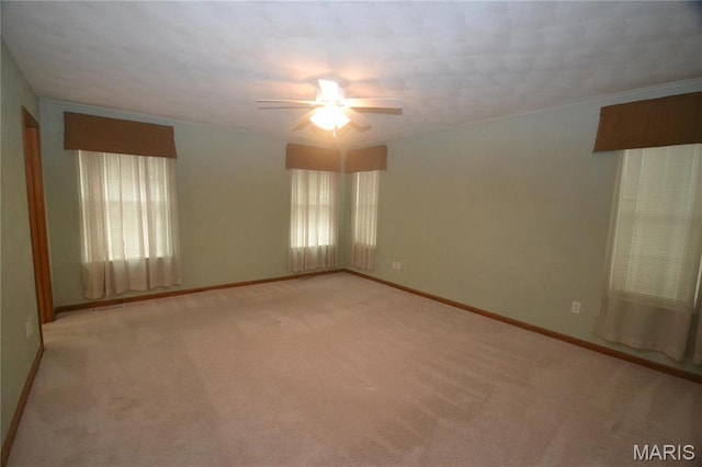 spare room with a ceiling fan, light carpet, and baseboards