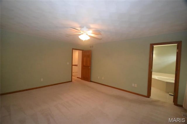 unfurnished bedroom featuring light colored carpet, baseboards, ensuite bathroom, and a ceiling fan