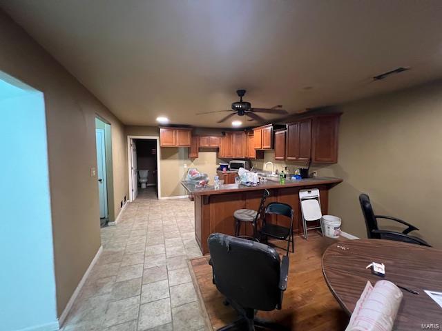 22585 Harlan Ln, Saint Robert, MO 65584 - kitchen with a peninsula, baseboards, ceiling fan, a breakfast bar area, and stainless steel microwave