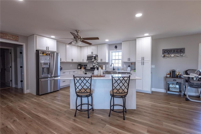 14822 Cedar Cove Pl, New London, MO 63459 - kitchen with appliances with stainless steel finishes, light countertops, white cabinetry, a center island, and ceiling fan