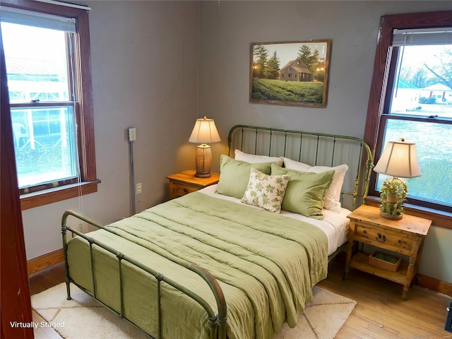 bedroom featuring wood finished floors, multiple windows, and baseboards