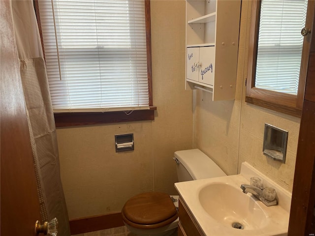 bathroom featuring toilet, tile walls, and vanity