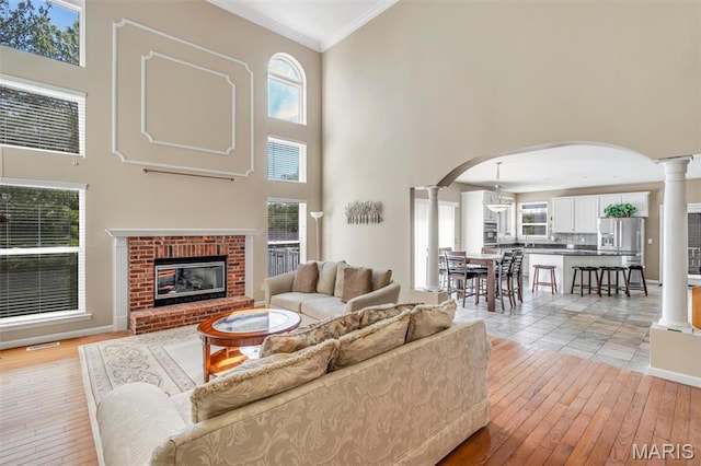 406 Clayton Hollow Dr, Wildwood, MO 63005 - living area featuring decorative columns, a towering ceiling, arched walkways, light wood-style flooring, and ornamental molding