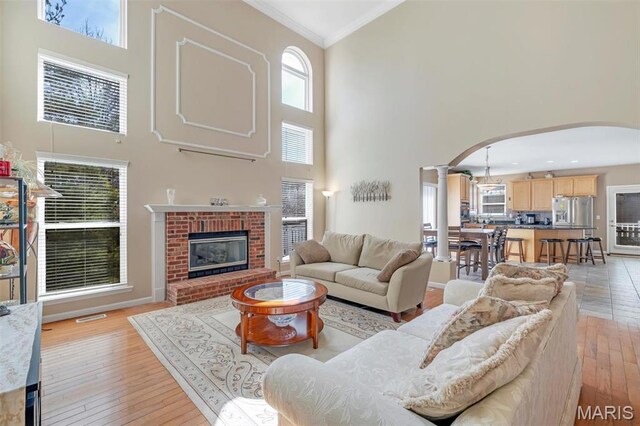 406 Clayton Hollow Dr, Wildwood, MO 63005 - living room featuring a high ceiling, arched walkways, decorative columns, ornamental molding, and light wood-style floors