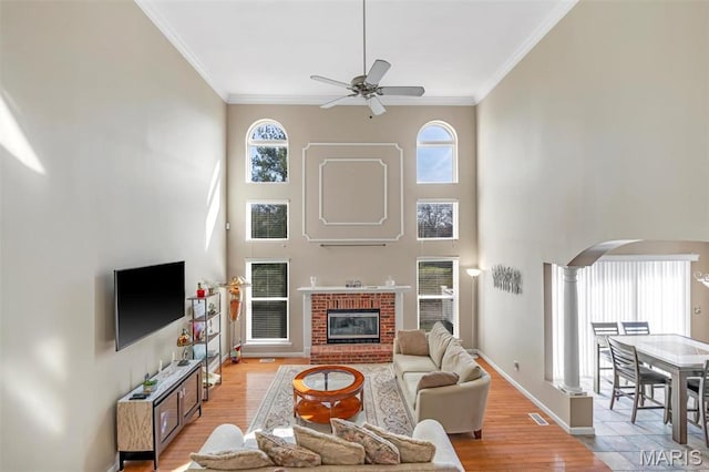 406 Clayton Hollow Dr, Wildwood, MO 63005 - living room featuring a ceiling fan, arched walkways, a high ceiling, crown molding, and light wood-style flooring
