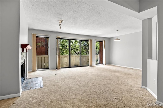 unfurnished living room featuring carpet floors, a brick fireplace, a textured ceiling, and baseboards