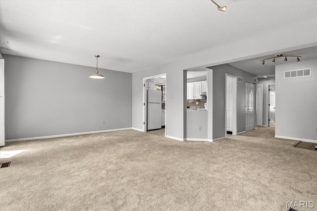 unfurnished living room with light carpet, baseboards, and a textured ceiling