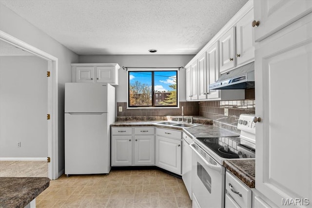 kitchen featuring white appliances, a sink, under cabinet range hood, dark countertops, and white cabinets